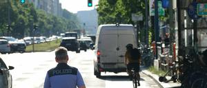 Transporter parkt auf Radweg, Radfahrer muss ausweichen, Polizist beobachtet.