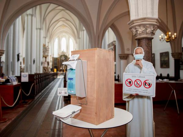 Ein Desinfektionsmittelspender und ein Aufsteller eines Geistlichen mit Mund-Nasen-Schutz im Eingangsbereich der St. Marienkirche.