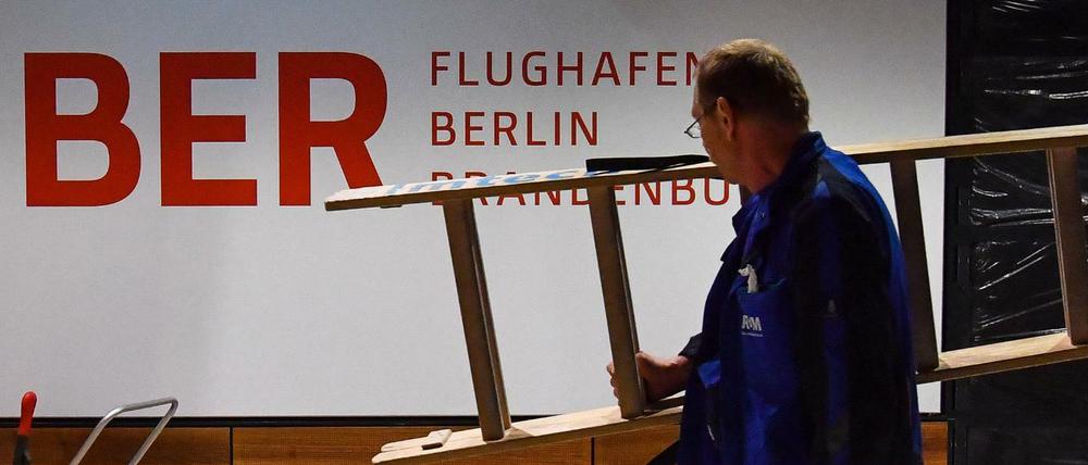 Ein Arbeiter trägt eine Leiter in einem Gebäude des Hauptstadtflughafens Berlin Brandenburg Willy Brandt (BER).