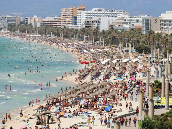 Urlauber tummeln sich dicht an dicht in der Hochsaison am Strand von El Arenal, Mallorca, Spanien. 