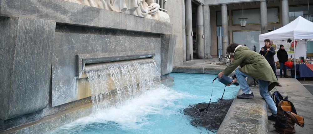 Ein Aktivist der Extinction Rebellion schüttet eine schwarze Flüssigkeit in den Brunnen „La Dora“ als Geste gegen Dürre und Flussverschmutzung.