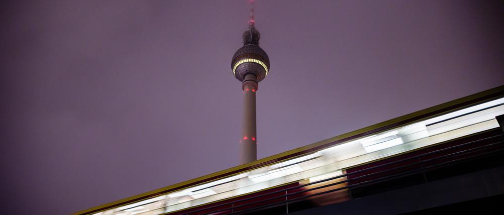 Eine S-Bahn fährt am Morgen vor dem Berliner Fernsehturm aus dem Bahnhof Alexanderplatz. (Bewegungsunschärfe durch lange Belichtungszeit)