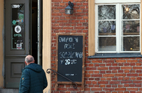 Ein Schild mit der Aufschrift "Eintritt nur mit Maske Sitzplätze innen mit 2G Genesen oder Geimpft" ist in der Potsdamer Innenstadt neben dem Eingang zu einem Café angebracht. Foto: Soeren Stache/dpa
