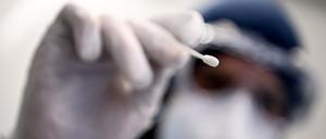 Ein Arzt hält ein Teststäbchen für die Entnahme einer Probe für einen PCR-Test in der Hand. 