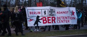 Teilnehmer einer Demonstration gegen den Bau eines geplanten Abschiebezentrums am Flughafen Berlin Brandenburg BER tragen Transparente. 