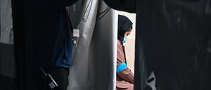 Eine Frau, die zusammen mit weiteren Ortskräften aus Afghanistan am frühen Morgen auf dem Gelände der DRK-Flüchtlingshilfe in der Erstaufnahmeeinrichtung angekommen ist, sitzt in einem Zelt. 
