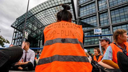 Eine Klimaaktivistin der Gruppe „Letzte Generation“ trägt eine Warnweste mit der Aufschrift: „Before the tipping point“ („Vor dem Kipppunkt“), als sie am 13. September 2023 den Verkehr vor dem Hauptbahnhof in Berlin blockiert.
