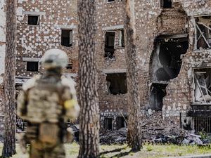 Ein ukrainischer Soldat steht vor einem zerstörten Gebäude in Irpin (Symbolbild)
