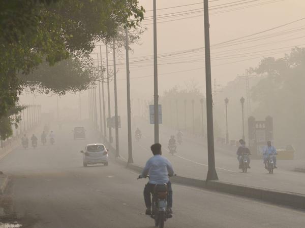 Pakistaner bahnen sich am 18. Juli 2022 in Lahore einen Weg durch den Smog.