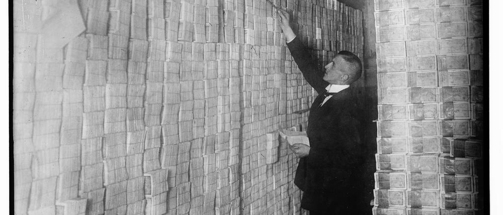Ein Angestellter zählt 1923 Geldscheinstapel in einer Berliner Bank.