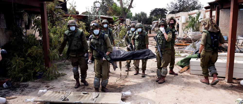 Israelische Soldaten tragen im Kibbuz Kfar Aza nach dem Massaker der Hamas eine Leiche weg.