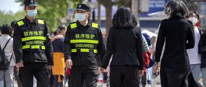 Sicherheitsbeamte mit Gesichtsmasken patrouillieren entlang einer Einkaufsstraße in Peking.
