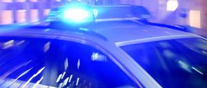 Ein Streifenwagen der Polizei steht mit eingeschaltetem Blaulicht auf der Straße. 