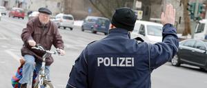 Ein Polizist stoppt einen Fahrradfahrer an der Kaiser-Wilhelm-Straße für eine Verkehrskontrolle.