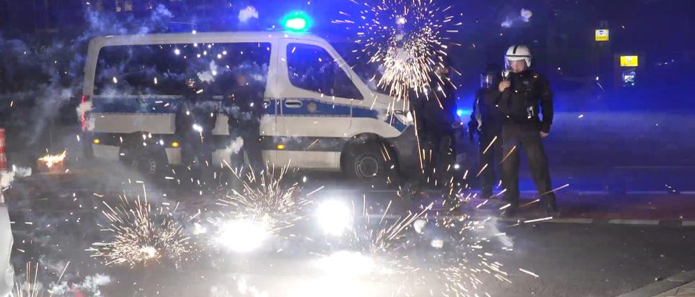 Polizeibeamte stehen hinter explodierendem Feuerwerk. Nach Angriffen auf Einsatzkräfte in der Silvesternacht hat die Diskussion um Konsequenzen begonnen. Berlins Regierende Bürgermeisterin will, dass sich die Innenminister mit dem Thema beschäftigen.