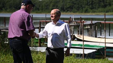 Händeschütteln – in der Hoffnung auf Hilfe: Bundeskanzler Olaf Scholz macht sich mit Eckhard Syring vom Angelverein Wildenbruch ein Bild vom See.