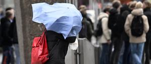 Ein Schirm fliegt einer Dame in Köln sturmbedingt um den Kopf.