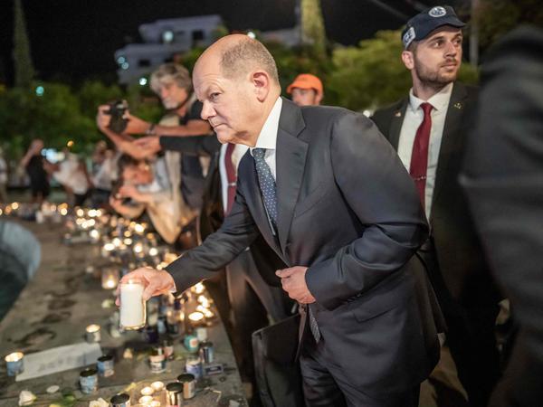 Der deutsche Bundeskanzler Olaf Scholz zündet eine Kerze an einer behelfsmäßigen Gedenkstätte am Brunnen auf dem Dizengoff-Platz in Tel Aviv an.