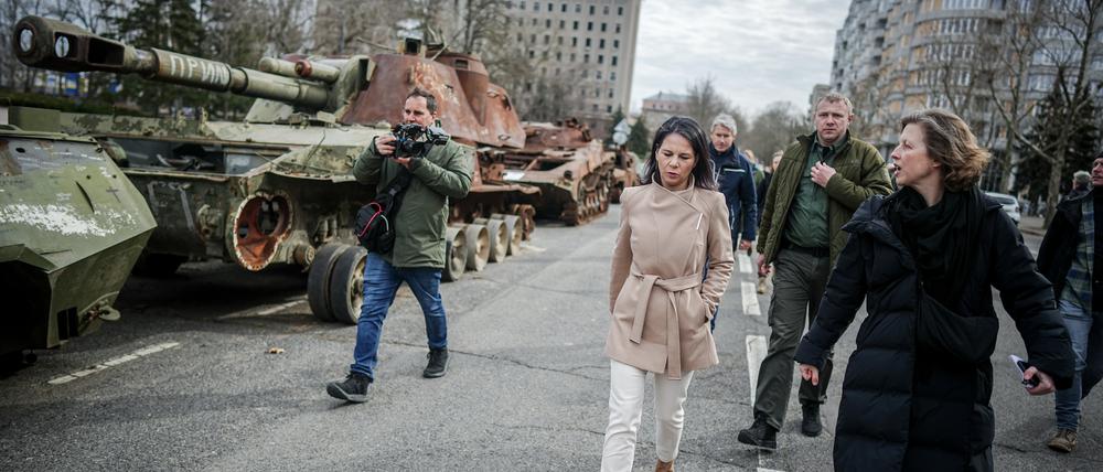 Annalena Baerbock (Bündnis 90/Die Grünen, M), Außenministerin, geht bei ihrem Besuch im Februar  des ehemaligen Sitz der Regionalverwaltung der Oblast Mykolajiw an zerstörten russischen Panzern vorbei.  