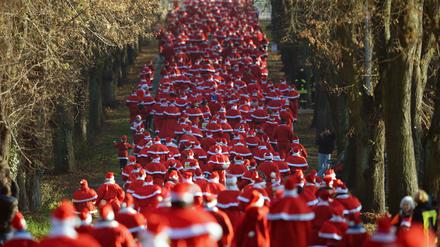 Hunderte Läufer in Weihnachtsmannkostümen laufen am 07.12.2014 in Michendorf (Brandenburg) während des traditionellen Weihnachtsmannlaufes durch eine Allee. Das Laufevent findet zum sechsten Mal statt. Foto: Ralf Hirschberger/dpa +++(c) dpa - Bildfunk+++