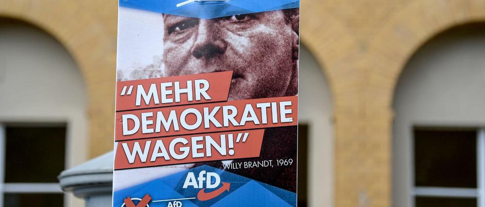 Ein Plakat mit einem Bild des SPD-Politikers Willy Brandt - und der Aufschrift "Mehr Demokratie wagen" der AfD hängt am Bahnhof von Michendorf.