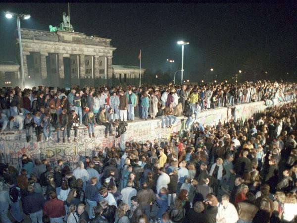 Menschen auf der Berliner Mauer vor dem Brandenburger Tor in der Nacht vom 9. auf den 10. November 1989.
