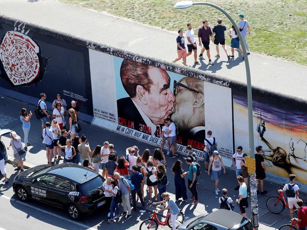 Touristen im Sommer 2019 auf beiden Seiten der East Side Gallery auf den Resten der Berliner Mauer
