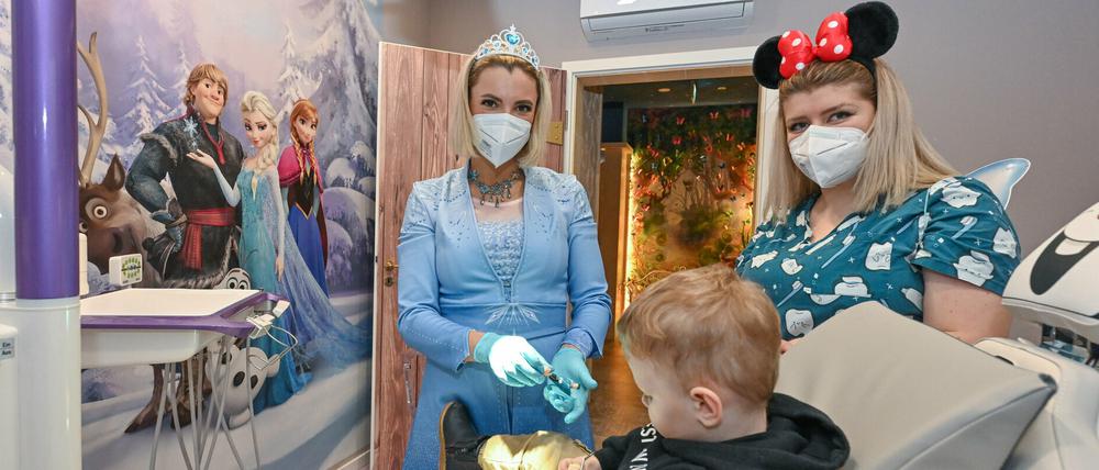 Kinderzahnärztin Anne Heinz verkleidet sich als Eiskönigin Elsa,  Arzthelferin Ari Dema hat ihren Sohn Diar mitgebracht.