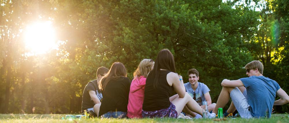 Jugendliche sitzen in den letzten Sonnenstrahlen am Tiergarten. 