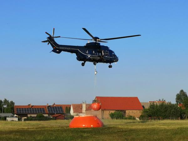 Ein Hubschrauber der Bundespolizei nimmt mit einem Löschwasser-Außenlastbehälter nahe Jüterbog Wasser auf. 