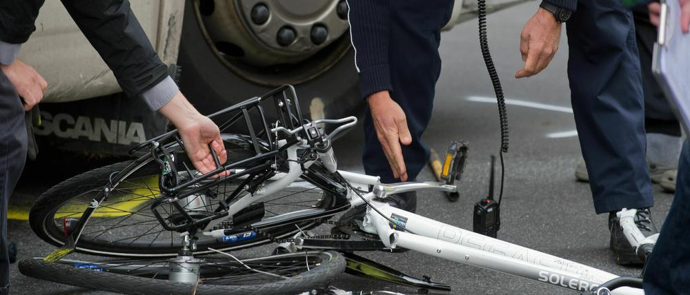 Polizisten und Gutachter bergen am in Berlin ein zertrümmertes Fahrrad unter einem Lkw nach einem Unfall (Archivbild vom 25.04.2012).