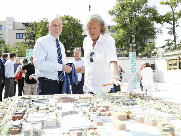 Friedhelm Schatz zeigt Ministerpräsident Dietmar Woidke (SPD) bei der Grundsteinlegung für das Depot im August 2019 die Pläne für das Areal der Medienstadt Babelsberg.