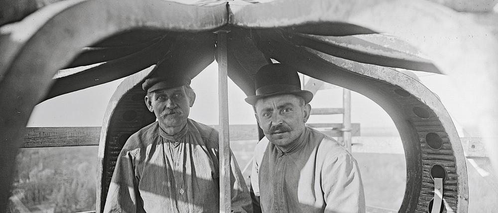 Zwei Handwerker in der Krone auf dem Dach des Neuen Palais' (um 1910).