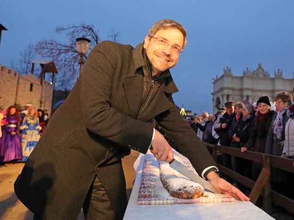 Oberbürgermeister Mike Schubert (SPD) schneidet traditionell den Weihnachtsstollen für die Besucher an.