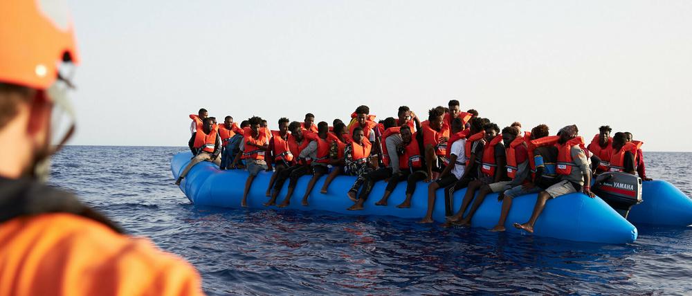 Ein Seenotretter schaut zu einem Flüchtlingsboot. 