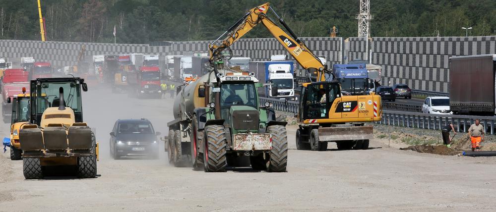 Traktoren verteilen Wasser auf der Baustelle der A10 bei Michendorf, damit es nicht so staubt.