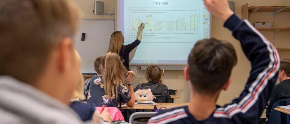 In einer 9. Klasse erklärt eine Lehrerin geometrische Figuren am Smartboard, Schüler:innen melden sich.